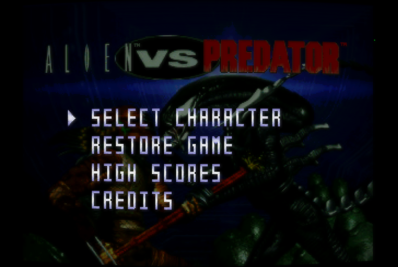 The same Alien vs Predator menu through the crt-gdv-mini-ultra-trinitron shader preset, in the same 4:3 frame, with vertical aperture-grille phosphor stripes, faint scanlines and a soft glow like a Sony Trinitron tube.